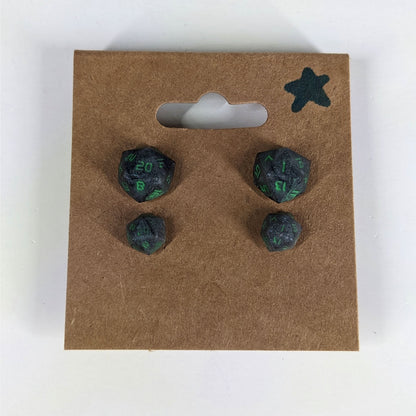 Two pairs of handmade d20 earrings with sterling silver hardware that are black and silver with acid green numbers on a kraft brown earring card with a star in the top right corner. The earrings on the left of each pair centers the 20 face and the earrings on the right of each pair centers the 1 face.