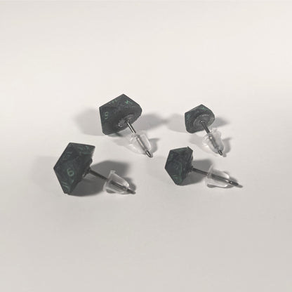 Two pairs of handmade d20 earrings that are black with a touch of silver with acidic green numbers turned to show the titanium hardware and bell shaped rubber backs.