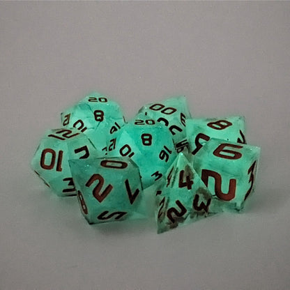 A complete set of 8 polyhedral dice that are glowing green with orange numbers, showing the glow-in-the-dark feature of this dice set. The DnD dice set is arranged in a circle and features 2 D20s, one of which is in the center surrounded by the other 7 dice.