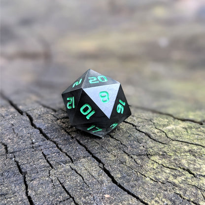 A standard d20 with black swirls and green numbers sits on a wood stump with the 20 face up.