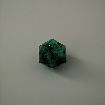 A high angle photo of a standard d20 glowing green with black swirls and green numbers with the 20 face up on a white background.