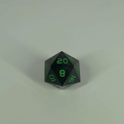 A high angle gif of a standard d20 with black swirls and green numbers with the 20 face up on a white background. The image shifts from regular light to darkness, where the die starts to glow green.