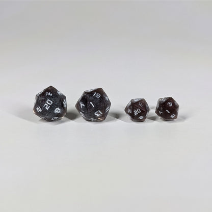 Two pairs of handmade d20 earrings with sterling silver hardware that are maroon and dark silver with white numbers on a white background sit in a line with the larger pair on the left and the smaller pair on the right. The earrings on the left of each pair centers the 20 face and the earrings on the right of each pair centers the 1 face.