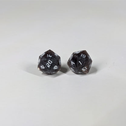 A single pair of the larger size handmade d20 earrings with sterling silver hardware that are maroon and dark silver with white numbers on a white background. The earring on the left centers the 20 face and the earring on the right centers the 1 face.
