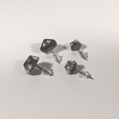Two pairs of handmade d20 earrings that are maroon and dark silver with white numbers turned to show the titanium hardware and bell shaped rubber backs.