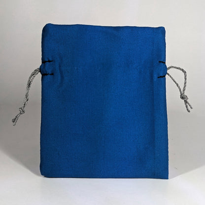 A small, handmade dice bag that is blue stands upright on a white background.