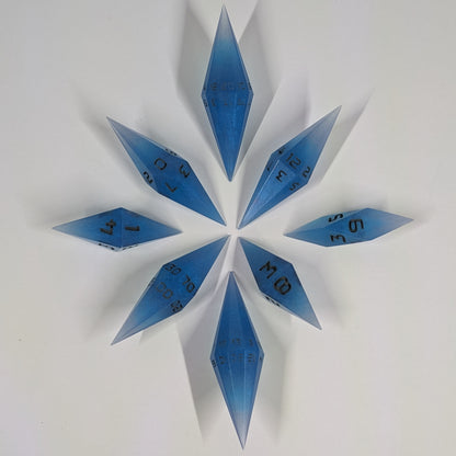 A complete set of resin dice featuring 2 d20s for advantage rolls. These electric blue swirls with grey numbering slender handmade diamond dice are clustered in a tight circle on a white background, highlighting the quality of the artisan dice craftsmanship and the unique pointed shape.