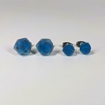 Two pairs of handmade d20 earrings that are swirls of blue with stormy gray numbers on a white background sit in a line with the larger pair on the left and the smaller pair on the right. The earrings on the left of each pair centers the 20 face and the earrings on the right of each pair centers the 1 face.