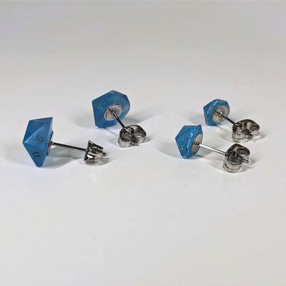 Two pairs of handmade d20 earrings that are swirls of blue with stormy gray numbers turned to show the metal alloy hardware and butterfly backs.