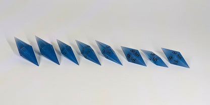 A mid angle photo of a complete set of handmade diamond DnD dice that are swirls of electric blue with grey numbers arranged in a straight line with bottom points angled slightly forwards and towards the right. They are lined up with the 2 d20s on the left going down to the d4 on the right side. The highest value number of each die is facing forward.