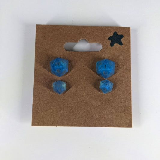 Two pairs of handmade d20 earrings with sterling silver hardware that are swirls of blue with stormy gray numbers on a kraft brown earring card with a star in the top right corner. The earrings on the left of each pair centers the 20 face and the earrings on the right of each pair centers the 1 face.