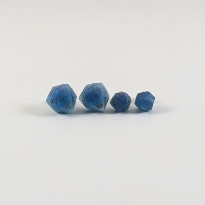 Two pairs of handmade d20 earrings with titanium hardware that are swirls of blue with stormy gray numbers on a white background sit in a line with the larger pair on the left and the smaller pair on the right. The earrings on the left of each pair centers the 20 face and the earrings on the right of each pair centers the 1 face.