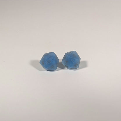 A single pair of the larger size handmade d20 earrings with titanium hardware that are swirls of blue with stormy gray numbers on a white background. The earring on the left centers the 20 face and the earring on the right centers the 1 face.