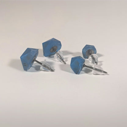 Two pairs of handmade d20 earrings that are swirls of blue with stormy gray numbers turned to show the titanium hardware and bell shaped rubber backs.