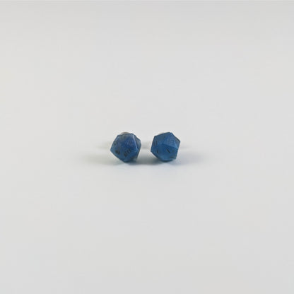 A single pair of the smaller size handmade d20 earrings with titanium hardware that are swirls of blue with stormy gray numbers on a white background. The earring on the left centers the 20 face and the earring on the right centers the 1 face.