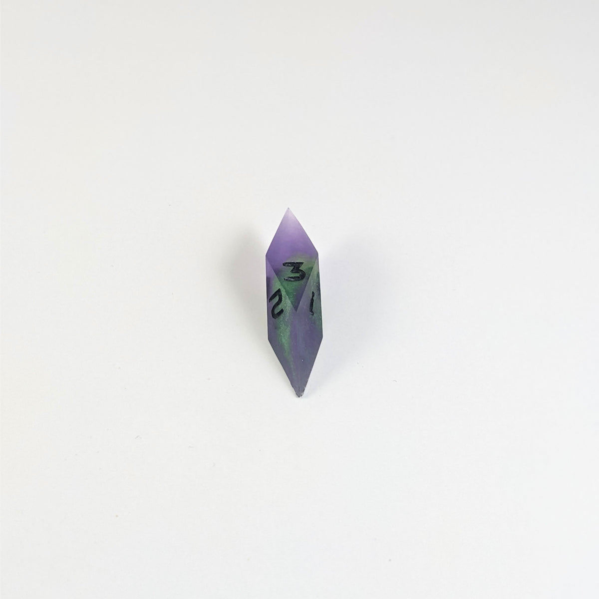 A mid angle view of a diamond d3 with swirls of purple and green with black numbers that glow in the dark on a white background.