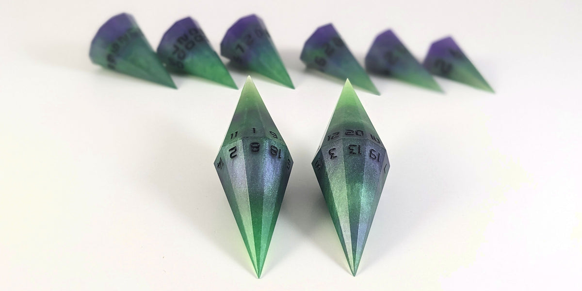 A straight on photo of a dagger set of DnD dice that are green and purple with black numbers that glow in the dark focusing on 2 d20s in the center. The d20 on the left has the 1 face up and the d20 on the right has the 20 face up. The other 6 dice are lined up in the background but are out of focus, while the d20s are in sharp focus.