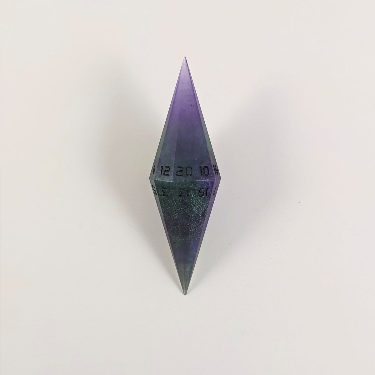 A high angle view of a diamond d20 with swirls of purple and green with black numbers that glow in the dark on a white background.