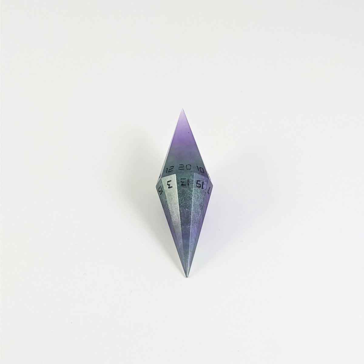 A mid angle view of a diamond d20 with swirls of purple and green with black numbers that glow in the dark on a white background.