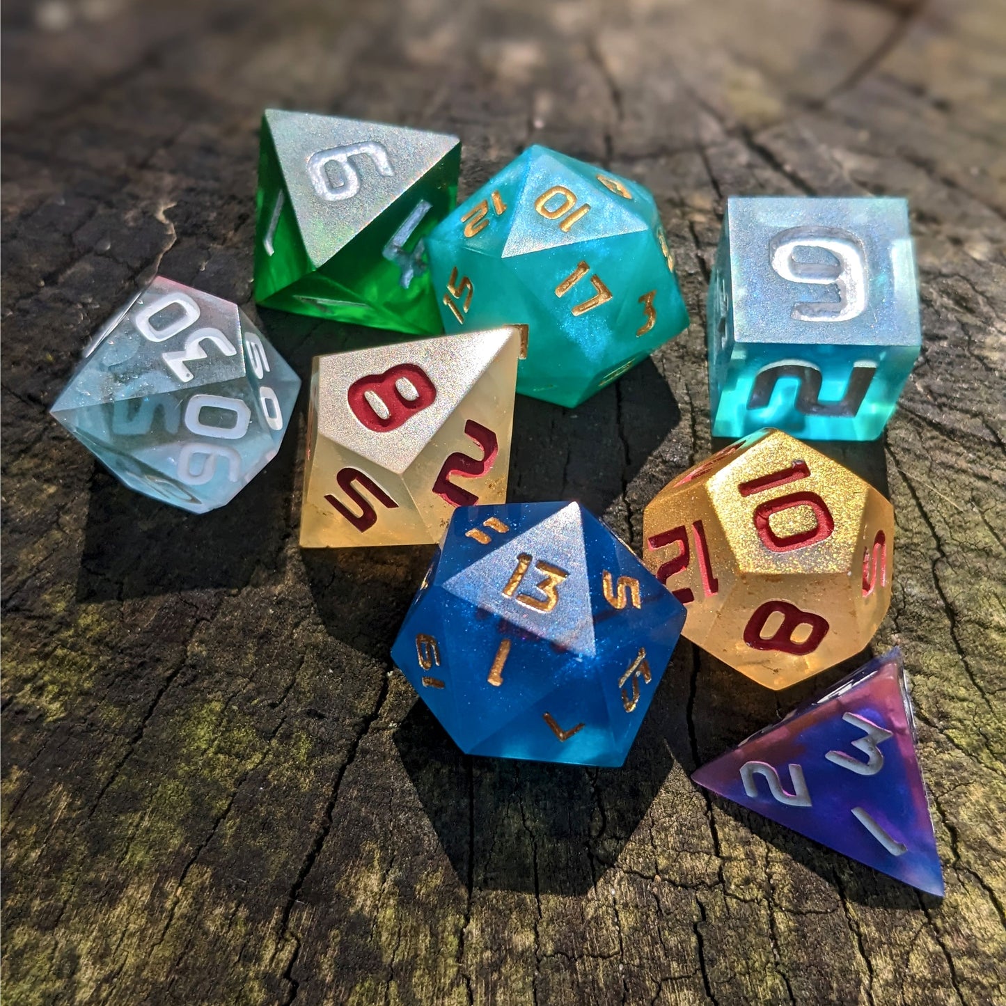 A set of polyhedral dnd dice that are a mismatched array of colors and designs sit on a wooden stump.