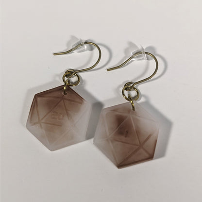 A pair of espresso brown and white dangly, flat d20 earrings with gold color titanium and niobium hardware and bell shaped rubber backs on a white background. The earring on the left has a 20 on it and the earring on the right has a 1 on it, both in a sci-fi style font.