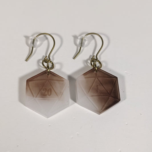 A pair of espresso brown and white dangly, flat d20 earrings with gold color titanium and niobium hardware and bell shaped rubber backs on a white background. The earring on the left has a 20 on it and the earring on the right has a 1 on it, both in a fantasy style font.