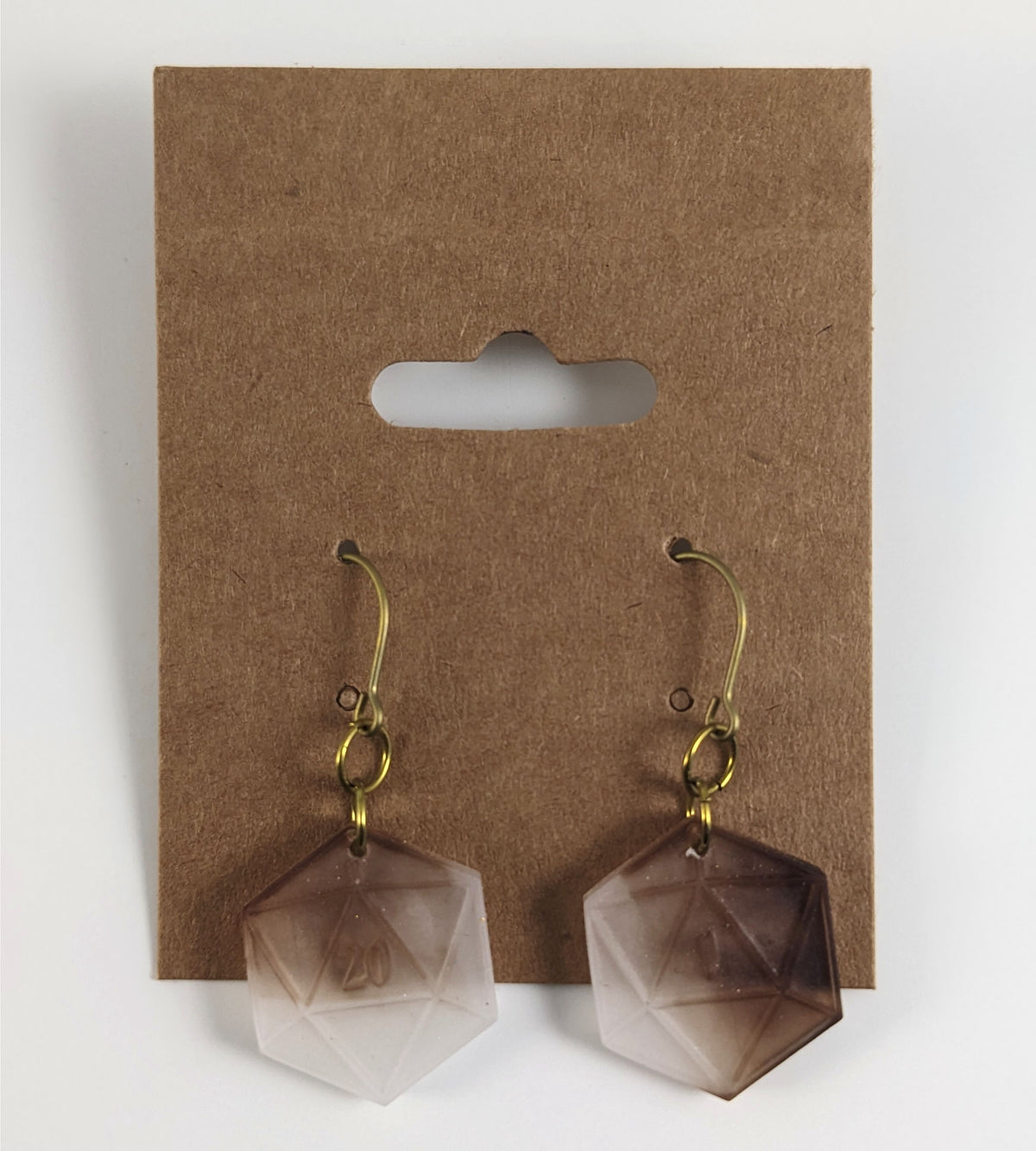 A pair of espresso brown and white dangly, flat d20 earrings with gold color titanium and niobium hardware on a kraft earring card on a white background. The earring on the left has a 20 on it and the earring on the right has a 1 on it, both in a fantasy style font.