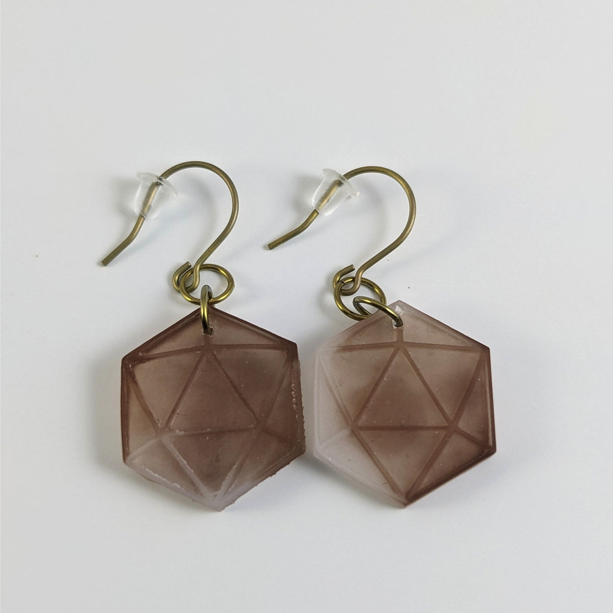 A pair of espresso brown and white dangly, flat d20 earrings with gold color titanium and niobium hardware and bell shaped rubber backs on a white background.