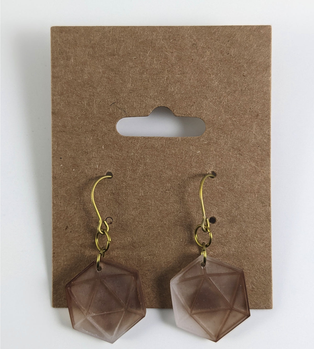 A pair of espresso brown and white dangly, flat d20 earrings with gold color titanium and niobium hardware on a kraft earring card on a white background.