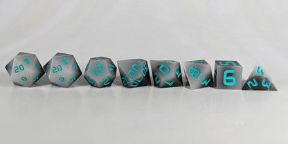 A straight on photo of a complete set of polyhedral dice that are coffee brown with milky white swirls and teal numbers arranged in a straight line. They are lined up with the 2 d20s on the left going down to the d4 on the right side. The highest value number of each die is facing forward