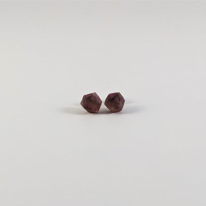 A single pair of the smaller size handmade d20 earrings with titanium hardware that are brown and white swirled with pink numbers on a white background. The earring on the left centers the 20 face and the earring on the right centers the 1 face.