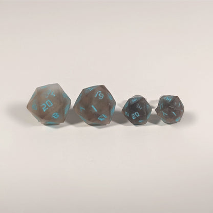 Two pairs of handmade d20 earrings with titanium hardware that are brown and white swirled with teal numbers on a white background sit in a line with the larger pair on the left and the smaller pair on the right. The earrings on the left of each pair centers the 20 face and the earrings on the right of each pair centers the 1 face.