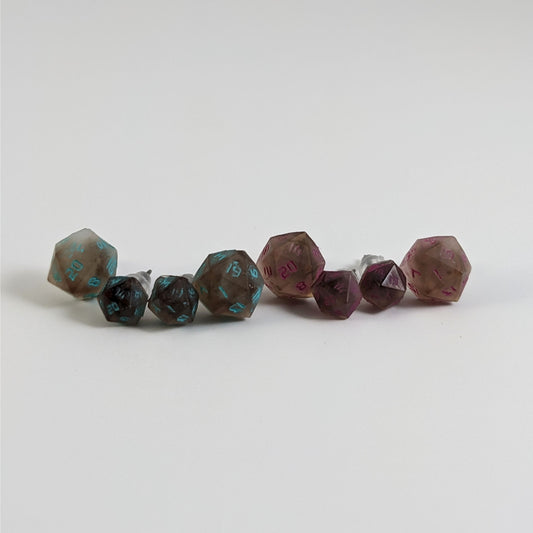 Four pairs of brown and white d20 stud earrings with titanium hardware on a white background. There are 2 large pairs and 2 small pairs, and one pair of each of those has teal numbers and pink numbers.