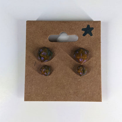 Two pairs of handmade d20 earrings with sterling silver hardware that are dark green and red gold with purple numbers on a kraft brown earring card with a star in the top right corner. The earrings on the left of each pair centers the 20 face and the earrings on the right of each pair centers the 1 face.
