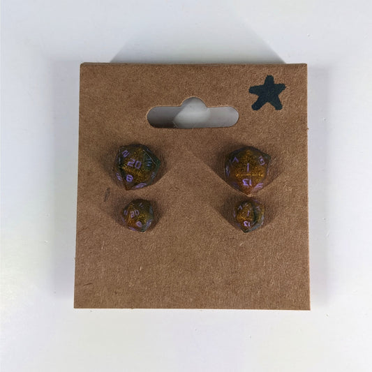 Two pairs of handmade d20 earrings with sterling silver hardware that are dark green and red gold with purple numbers on a kraft brown earring card with a star in the top right corner. The earrings on the left of each pair centers the 20 face and the earrings on the right of each pair centers the 1 face.