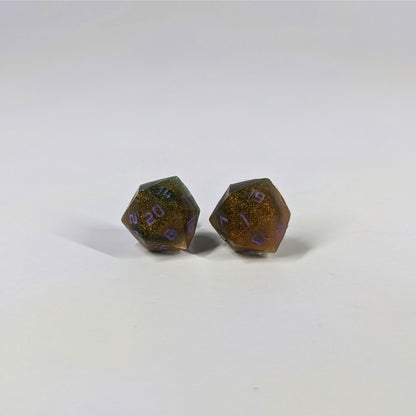A single pair of the larger size handmade d20 earrings with sterling silver hardware that are dark green and red gold with purple numbers on a white background. The earring on the left centers the 20 face and the earring on the right centers the 1 face.