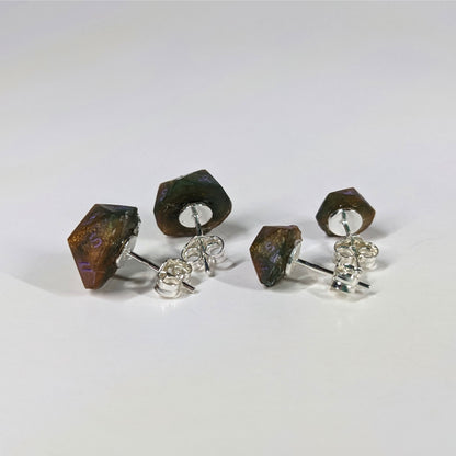 Two pairs of handmade d20 earrings that are dark green and red gold with purple numbers turned to show the sterling silver hardware and butterfly backs.