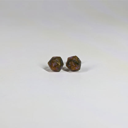 A single pair of the smaller size handmade d20 earrings with sterling silver hardware that are dark green and red gold with purple numbers on a white background. The earring on the left centers the 20 face and the earring on the right centers the 1 face.