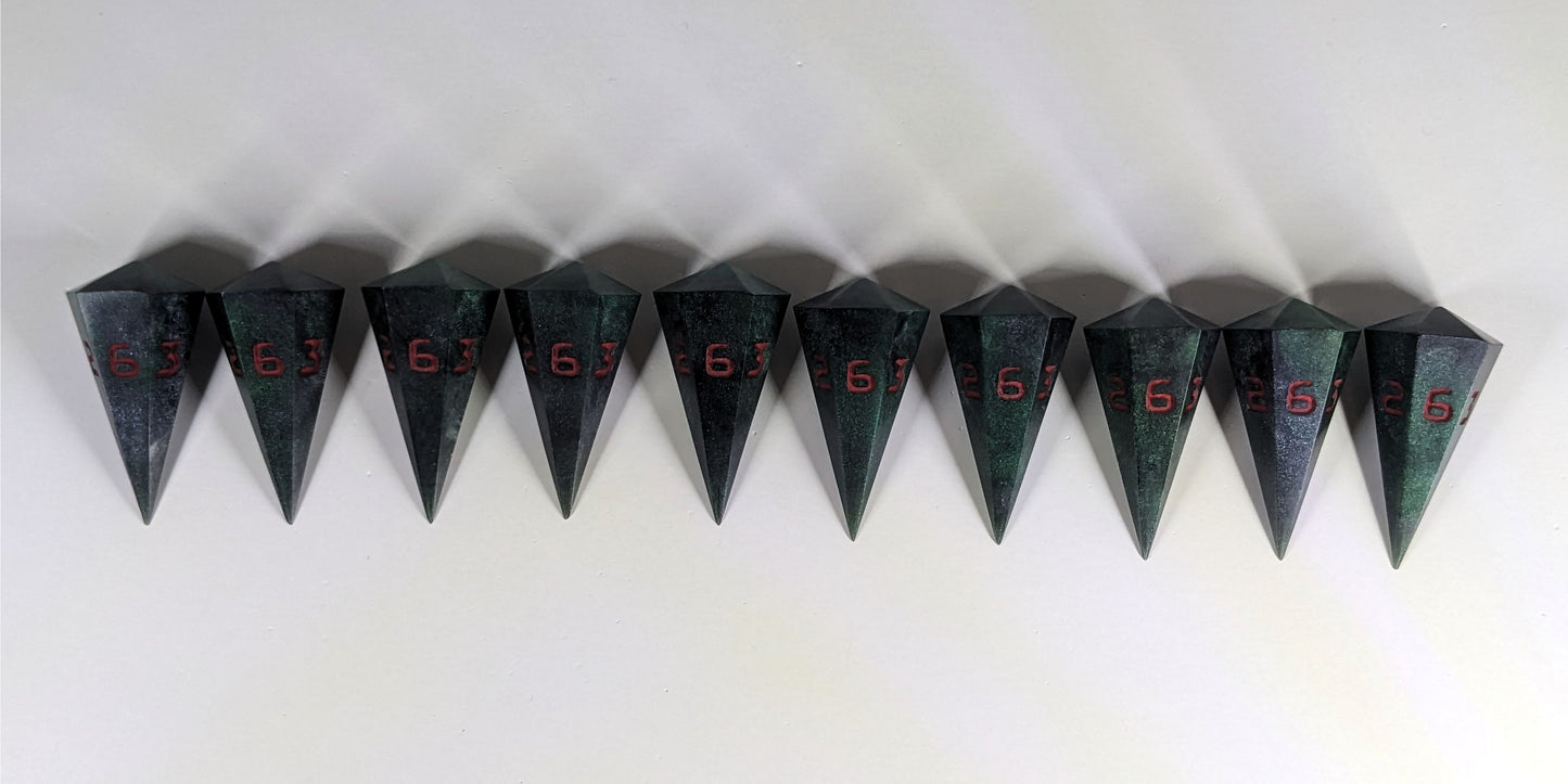 Ten dagger shaped d6s are arranged in a line with the points of the dice facing downwards. The dice are dark green and black with red numbers, and they all have the 6 face up.