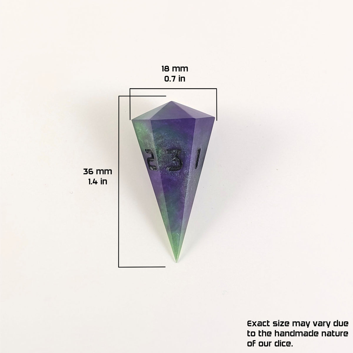 A size graphic of a dagger d3. The die is purple and green with black numbers. The die is 36 mm 1.4 in tall and 18 mm 0.7 in wide. The bottom right corner notes "Exact size may vary due to the handmade nature of our dice."