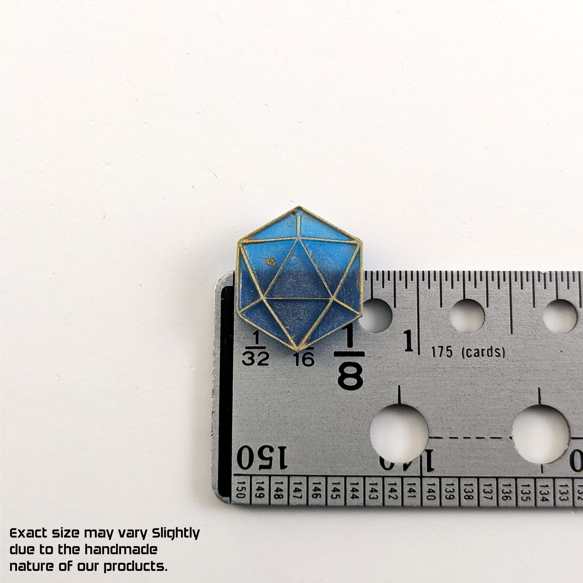 A graphic showing a blue and gold flat dangly d20 earring without a number or hardware on a ruler on a white background. The ruler shows the width of the d20 dangle as 0.68 inches or 17.33 mm. The bottom right corner has a disclaimer that reads, "Exact size may vary slightly due to the handmade nature of our products."