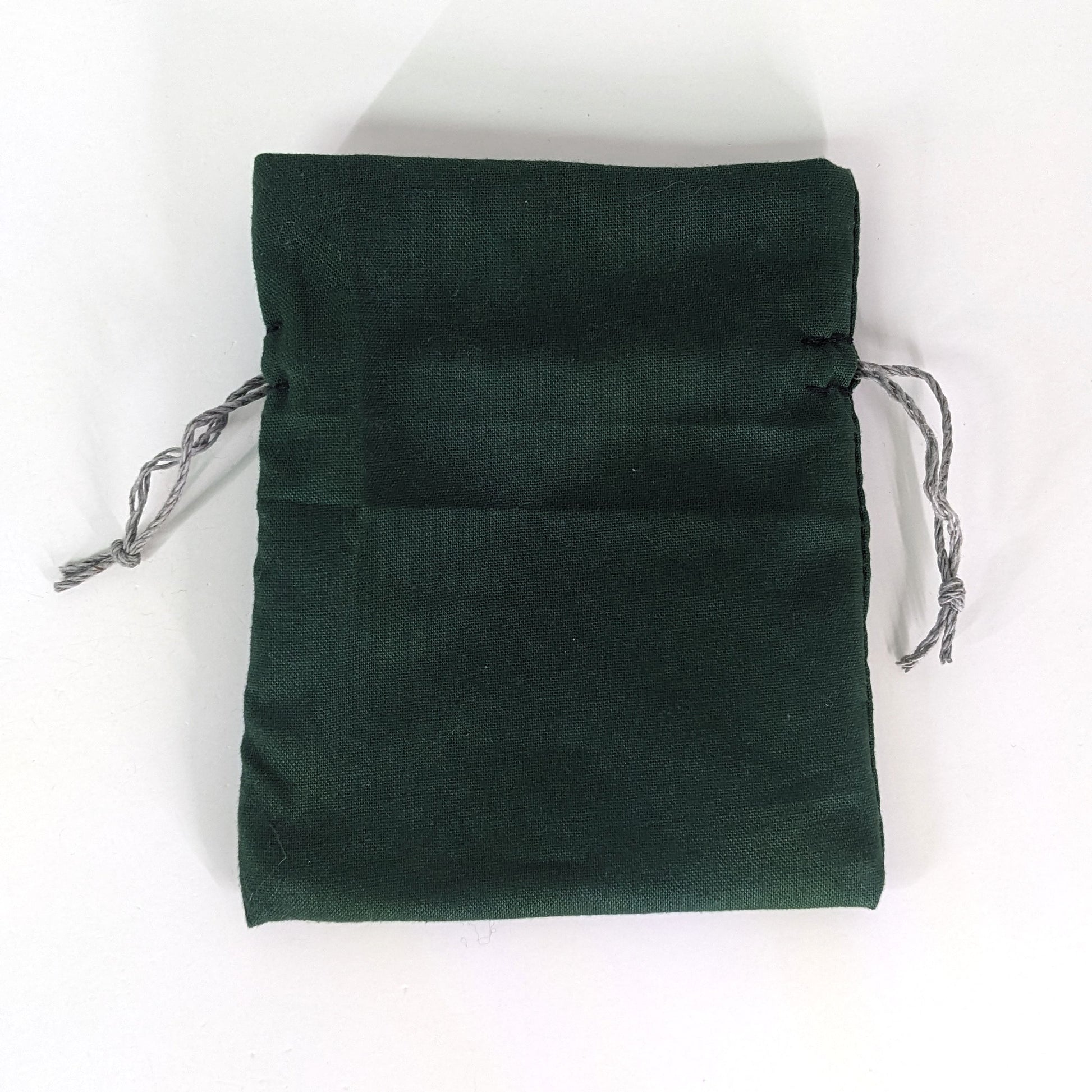 A small, handmade dice bag that is dark green lays flat on a white background.