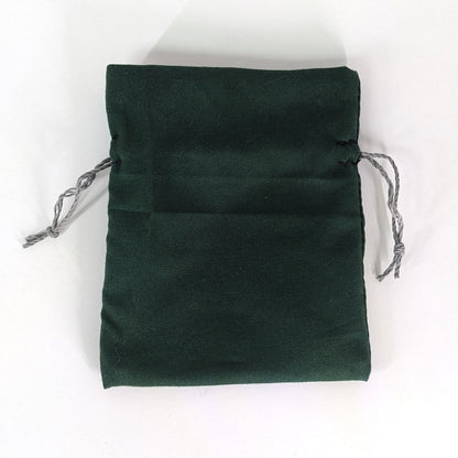 A small, handmade dice bag that is dark green lays flat on a white background.