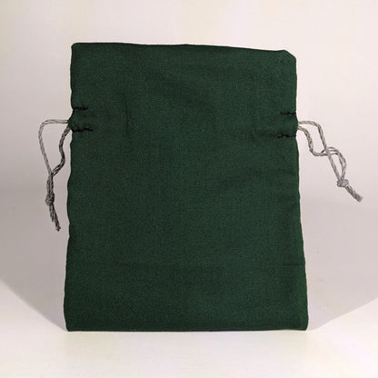 A small, handmade dice bag that is dark green stands upright on a white background.