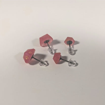 Two pairs of handmade d20 earrings that are bright pink with gold numbers turned to show the titanium hardware and bell shaped rubber backs.