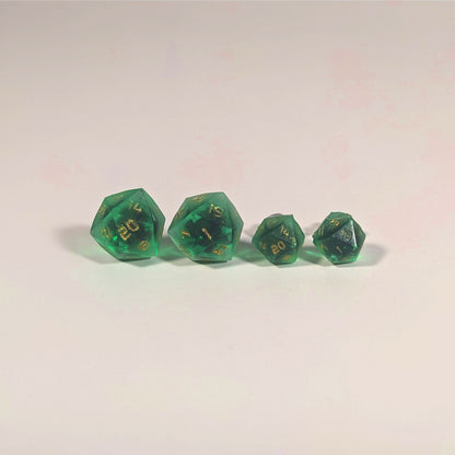 Two pairs of handmade d20 earrings with titanium hardware that are green with black flakies with gold numbers on a white background sit in a line with the larger pair on the left and the smaller pair on the right. The earrings on the left of each pair centers the 20 face and the earrings on the right of each pair centers the 1 face.