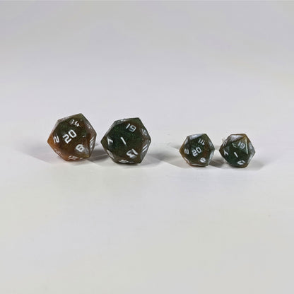 Two pairs of handmade d20 earrings with sterling silver hardware that are dark green and red gold with white numbers on a white background sit in a line with the larger pair on the left and the smaller pair on the right. The earrings on the left of each pair centers the 20 face and the earrings on the right of each pair centers the 1 face.