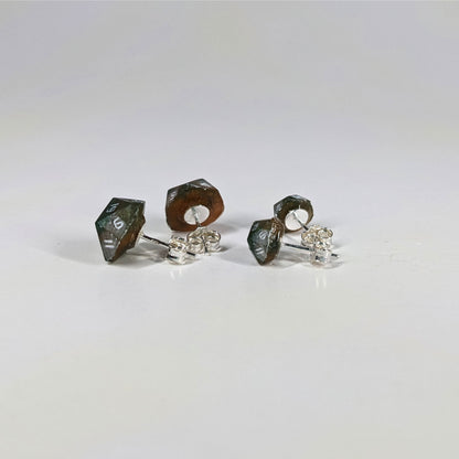 Two pairs of handmade d20 earrings that are dark green and red gold with white numbers turned to show the sterling silver hardware and butterfly backs.