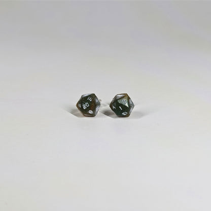 A single pair of the smaller size handmade d20 earrings with sterling silver hardware that are dark green and red gold with white numbers on a white background. The earring on the left centers the 20 face and the earring on the right centers the 1 face.