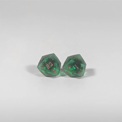 A single pair of the larger size handmade d20 earrings with titanium hardware that are emerald green with copper numbers on a white background. The earring on the left centers the 20 face and the earring on the right centers the 1 face.